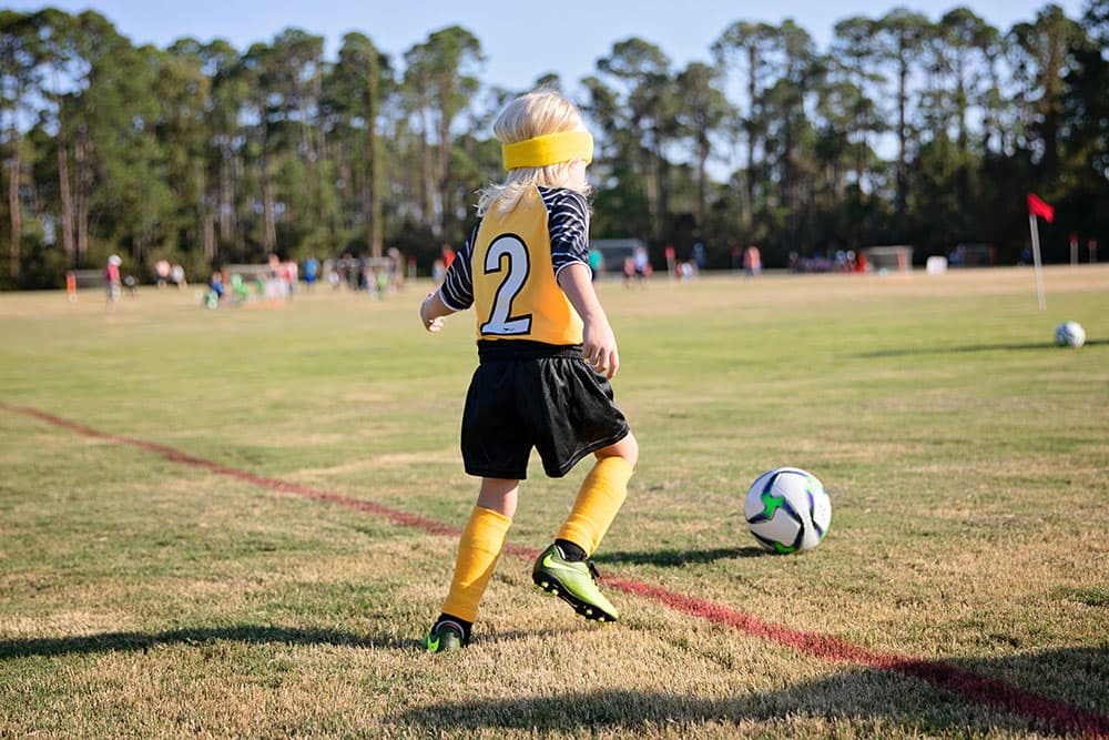 A young soccer player dribbles the ball.