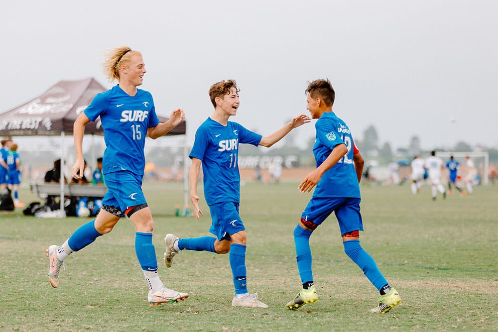Teammates from Surf FC celebrate a goal.
