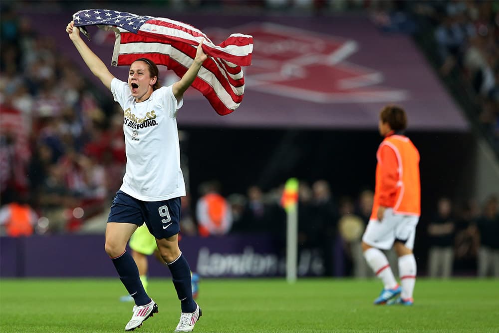 Heather O'Reilly celebrates with the American flag after defeating Japan to win gold at the London 2012 Olympic Games.